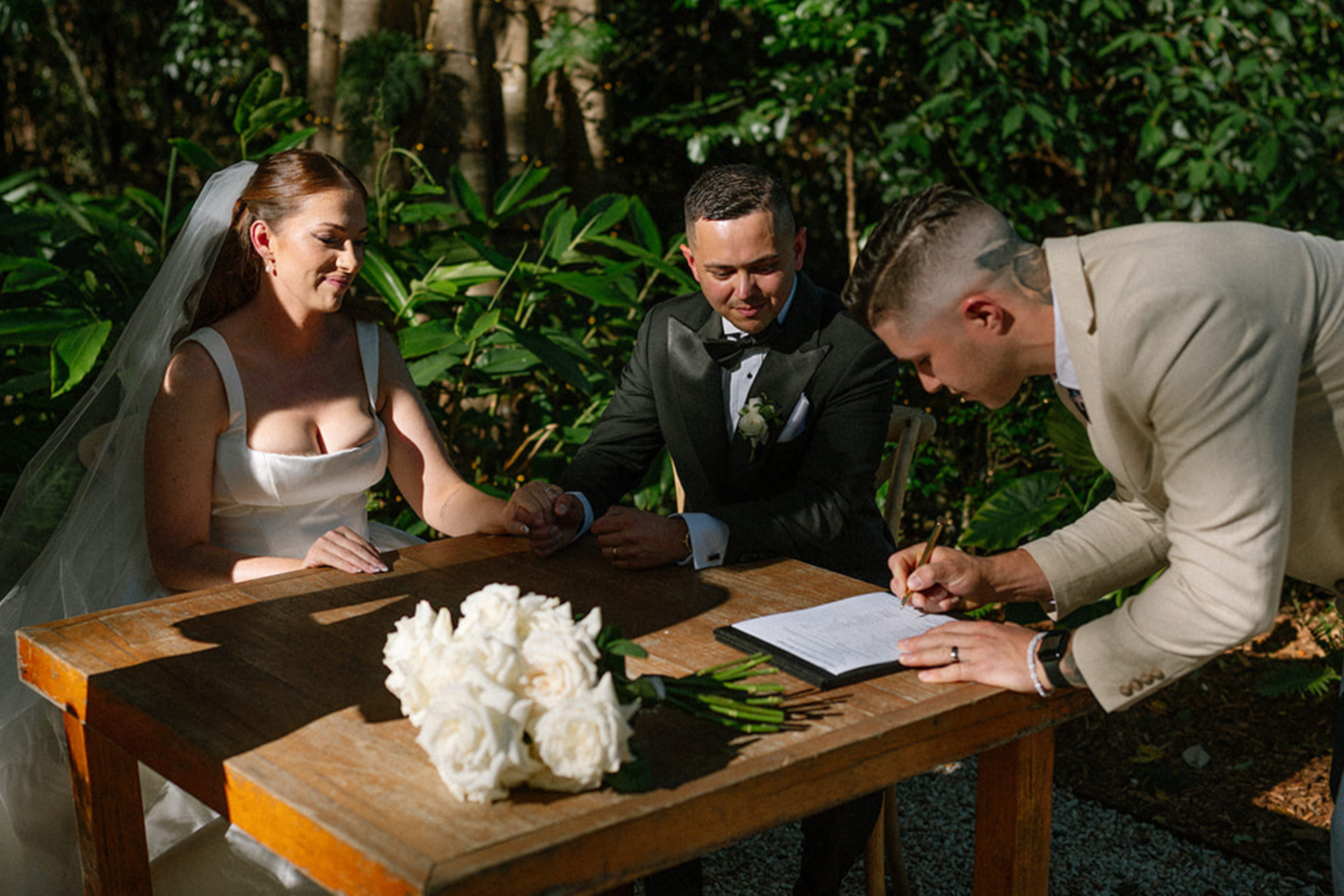 Couple signing the register at a timber table in the rainforest