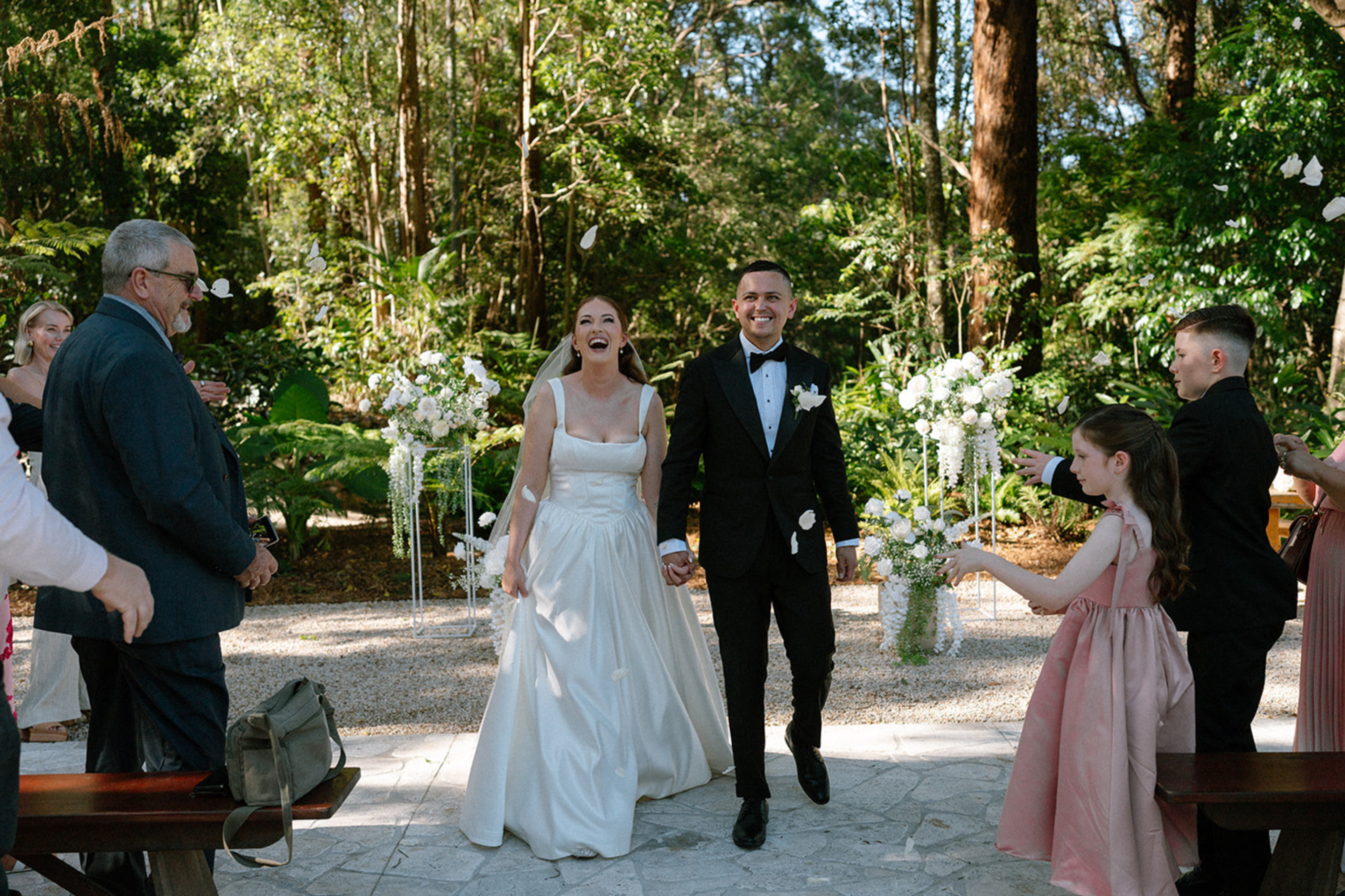 Newlyweds walking back down the aisle as guests celebrate