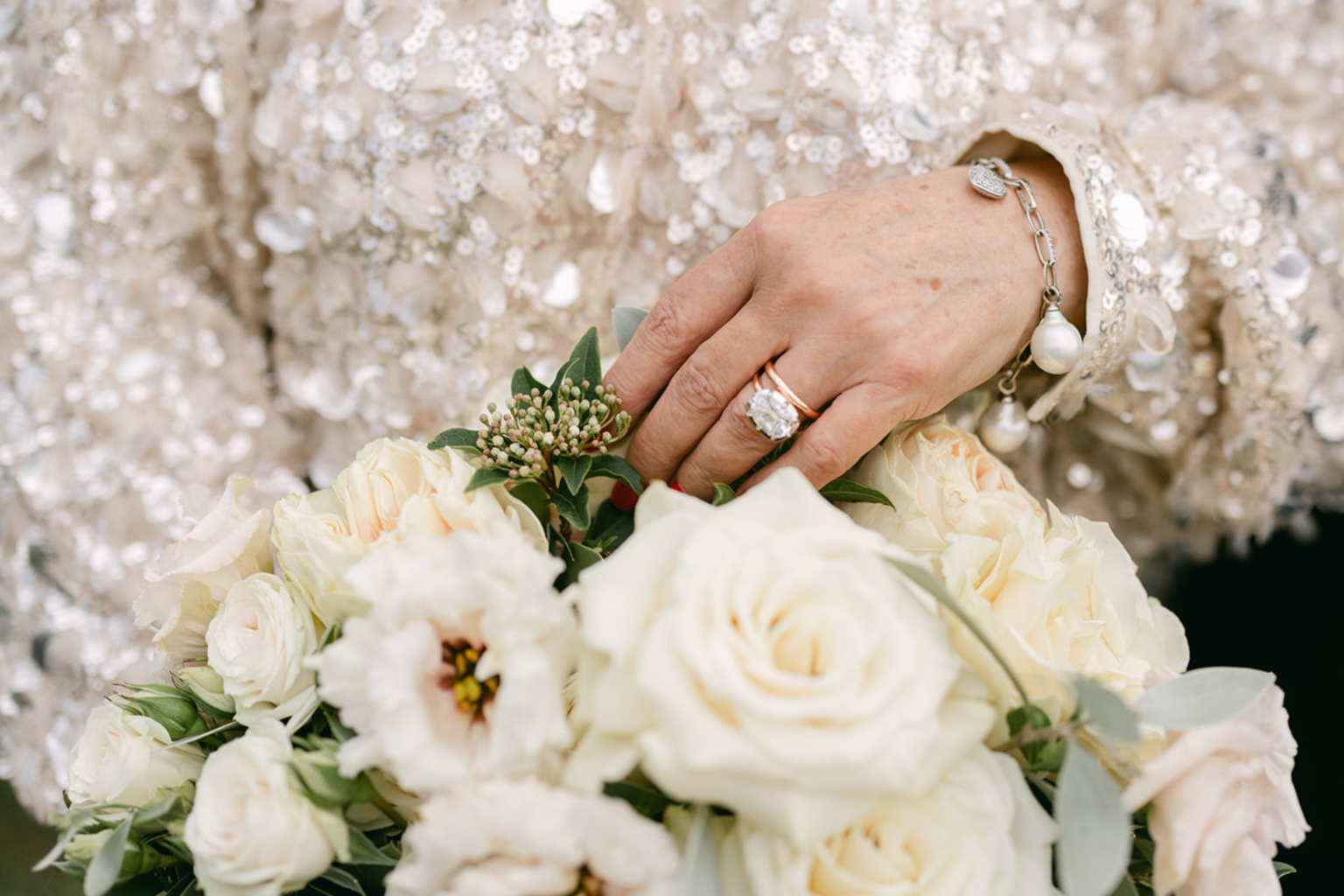 Close-up of a hand with rings resting on a rose bouquet